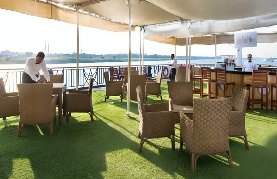 Waiter preparing tables on a sunny Nile cruise deck.
