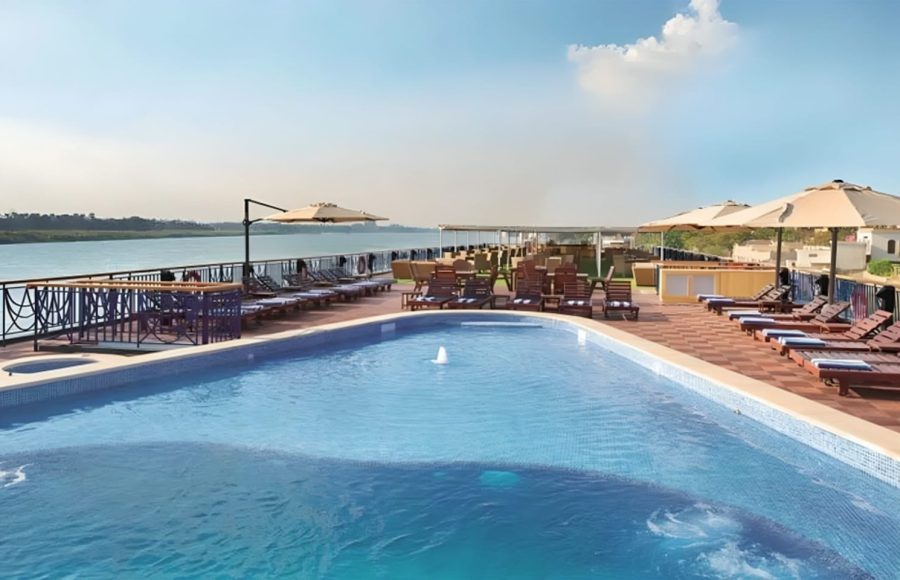 An outdoor swimming pool on a ship's sun deck overlooking the Nile River.