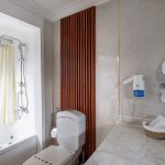 A modern and luxurious bathroom aboard the MS Chateau Lafayette Nile Cruise, featuring a bathtub with a shower, a sleek vanity, and high-end fixtures.