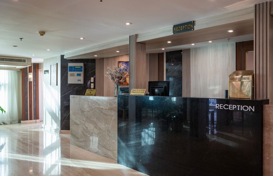 The elegant reception desk on the MS Chateau Lafayette Nile Cruise, featuring polished black marble, contemporary wood finishes, and a welcoming guest lobby setup.