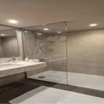 Modern cruise ship bathroom with a marble vanity, rectangular sink, and a walk-in glass shower enclosure.