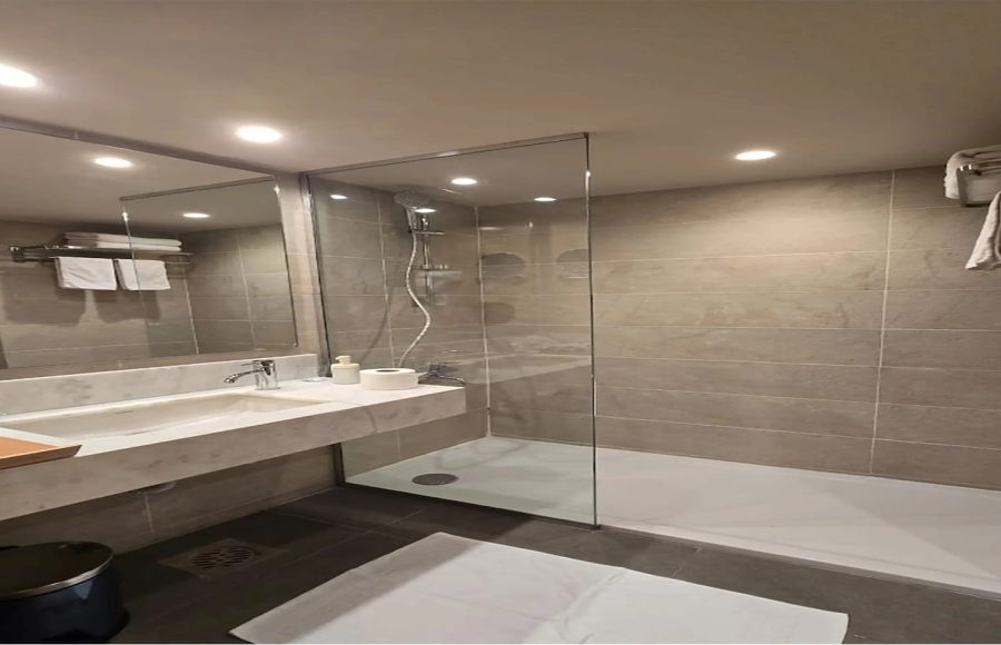 Modern cruise ship bathroom with a marble vanity, rectangular sink, and a walk-in glass shower enclosure.
