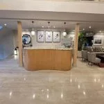 The modern reception area of the MS Ellie Nile Cruise with a light wood desk, marble floors, and a seating area nearby.