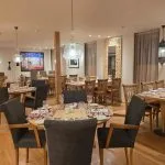 Interior view of the spacious dining room on the MS Ellie Nile Cruise with multiple tables, wood floors, and Middle Eastern-inspired decor.