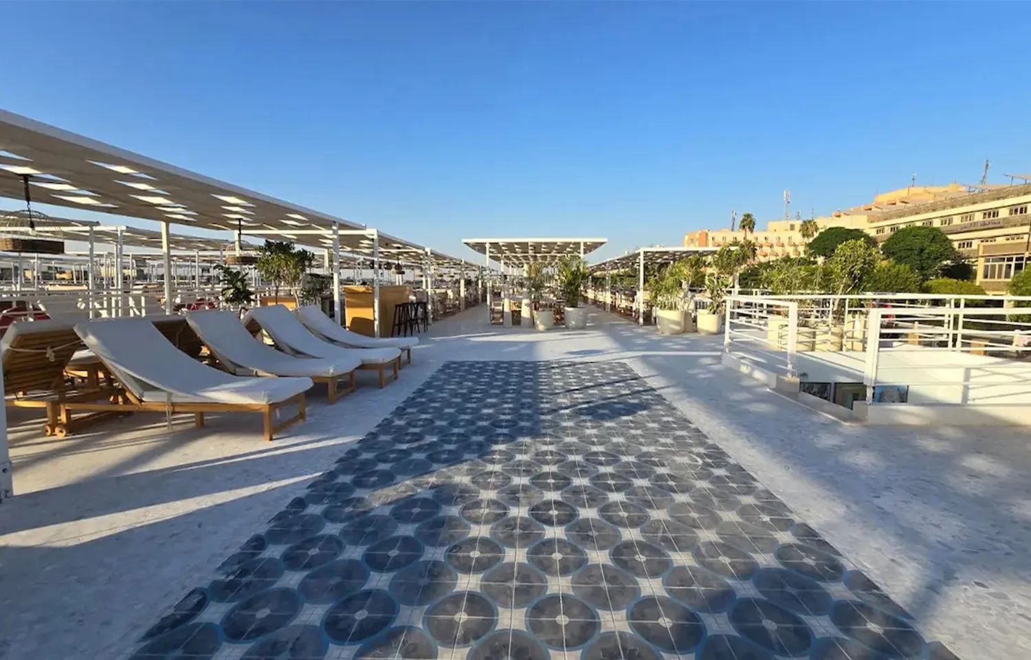 Sundeck of the MS Ellie Nile Cruise with rows of lounge chairs and patterned blue and white tile flooring under a blue sky.