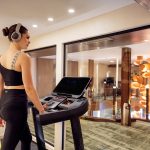 A guest working out on modern equipment in the gym aboard the MS Esmeralda Nile Cruise, featuring professional fitness machines and glass partitions overlooking the vessel's interior.