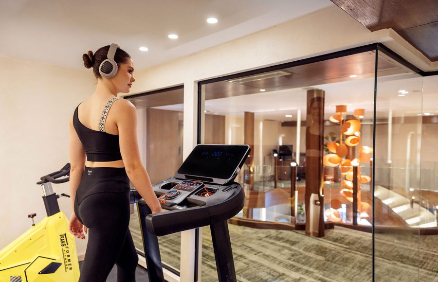 A guest working out on modern equipment in the gym aboard the MS Esmeralda Nile Cruise, featuring professional fitness machines and glass partitions overlooking the vessel's interior.