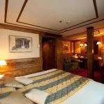 Deluxe wood-paneled suite bedroom with a king-sized bed and seating area.