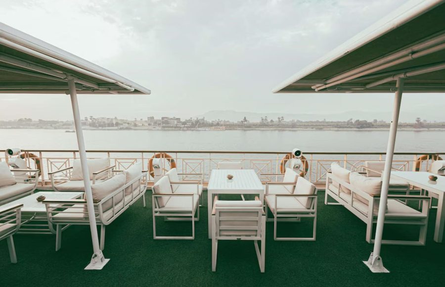 Sun deck pool area with blue and white striped loungers and turquoise umbrellas.