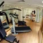 Ship gym with exercise equipment and an adjacent massage area.