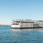 A cruise ship sailing the Nile River from Luxor to Aswan, a key part of the Egypt 12 Day Tour.