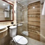 A modern and clean bathroom aboard the MS Nile Treasure Cruise, featuring a glass-enclosed walk-in shower, a stylish vanity sink, and warm marble-toned tiling.