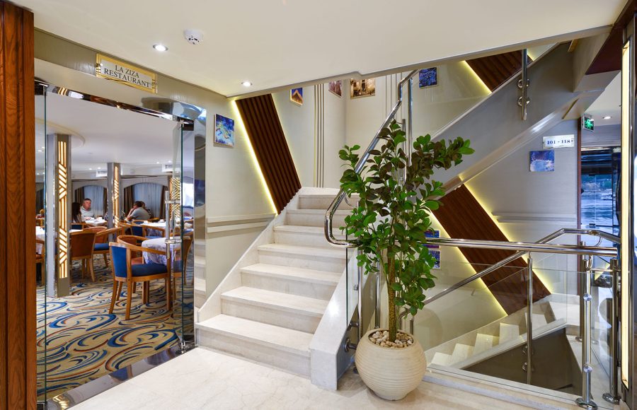 The entrance to the main restaurant aboard the MS Nile Treasure Cruise, featuring a bright modern staircase, sleek glass doors, and a welcoming interior view.