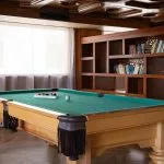 Billiards room on the MS Nile Plaza featuring a light wood pool table with a green felt, a coffered wood ceiling, and a large wooden bookshelf.