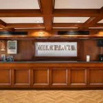 Interior reception desk of the MS Nile Plaza cruise ship, featuring rich wood paneling and a coffered ceiling.