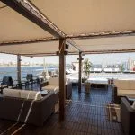 Covered sun deck and lounge area on the MS Nile Plaza overlooking the Nile River, with comfortable wicker seating and a visible swimming pool.