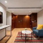Living area of a Nile cruise suite featuring blue armchairs, a patterned rug, dark wood paneling, and a white marble console table.