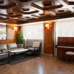 Elegant lounge on the MS Nile Plaza featuring a glossy wooden coffered ceiling, a piano, modern seating, and large windows.