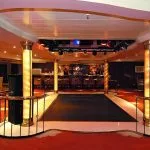 An indoor lounge and bar area on the MS Quest with a small dance floor and red carpeting.