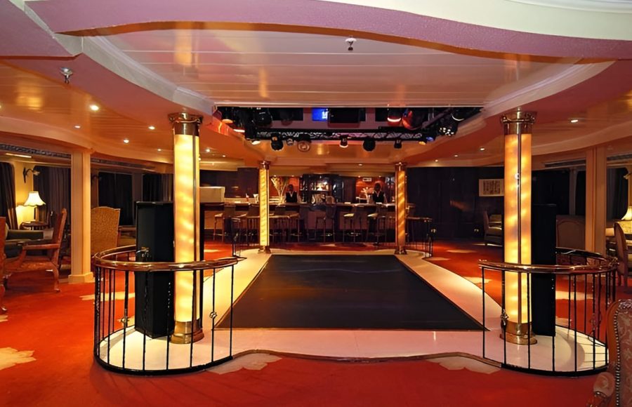 An indoor lounge and bar area on the MS Quest with a small dance floor and red carpeting.