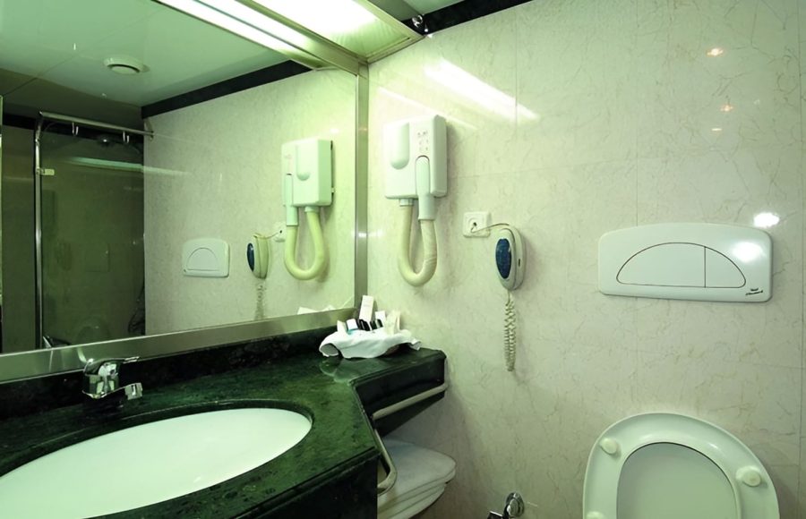 A clean, modern bathroom on the MS Quest Nile Cruise with a green marble vanity and white tiled walls.