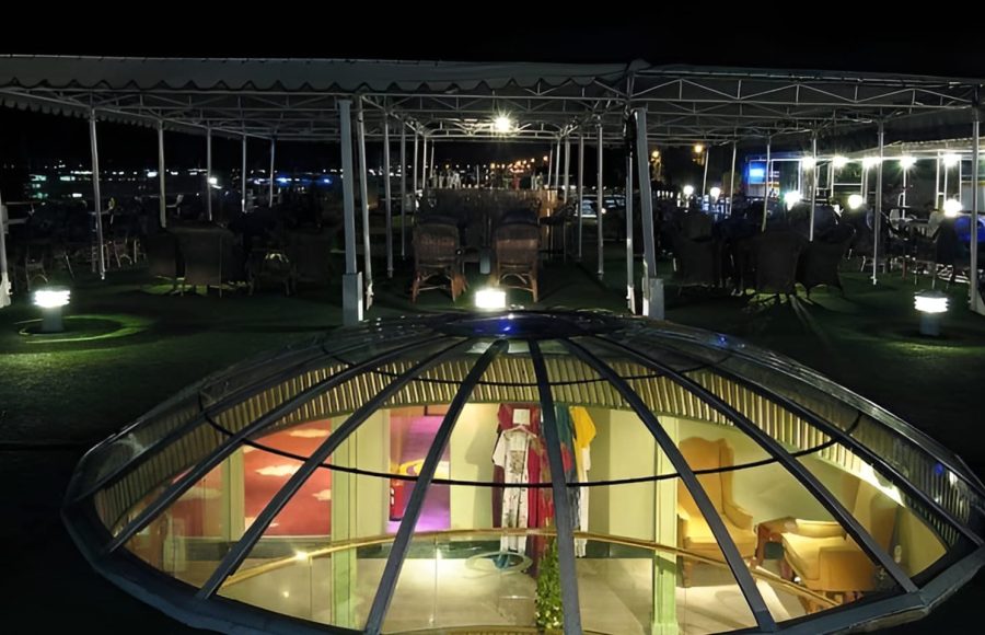 The top deck of the MS Quest at night featuring a glass skylight dome and outdoor seating under a canopy.