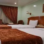 A traditional twin-bed cabin on the MS Quest Nile Cruise with large windows and a small seating area.