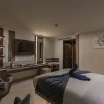 Luxury single or double cabin with a large bed, vanity/desk area, wall-mounted TV, and a towel swan decoration.