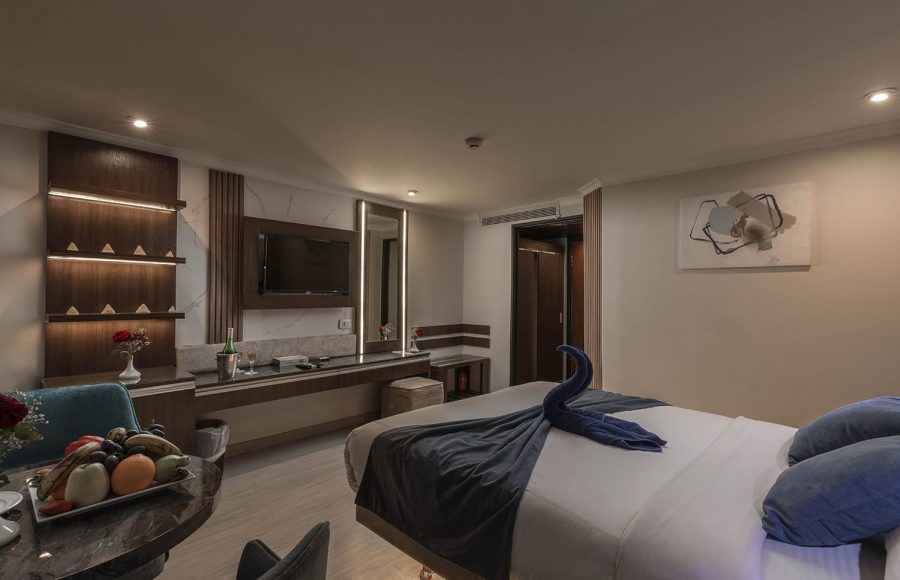 Luxury single or double cabin with a large bed, vanity/desk area, wall-mounted TV, and a towel swan decoration.