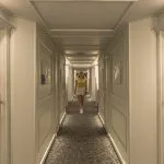 The stern view of the white, multi-deck MS Royal Beaurivage cruise ship sailing on the Nile near urban buildings.