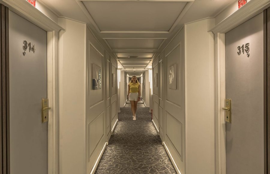 The stern view of the white, multi-deck MS Royal Beaurivage cruise ship sailing on the Nile near urban buildings.