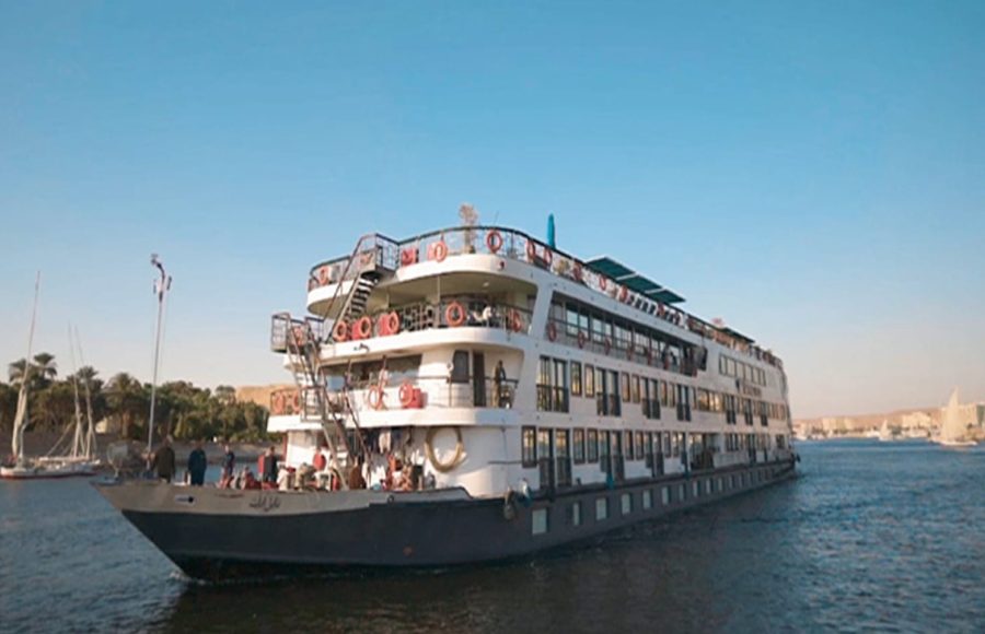 Three-quarter view of the multi-deck MS Royal Elite river cruise ship with life preservers and exterior stairs, sailing on the Nile River.