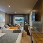 Cruise ship cabin with two twin beds, Egyptian-themed artwork above the headboard, and a towel swan accent on the bed.