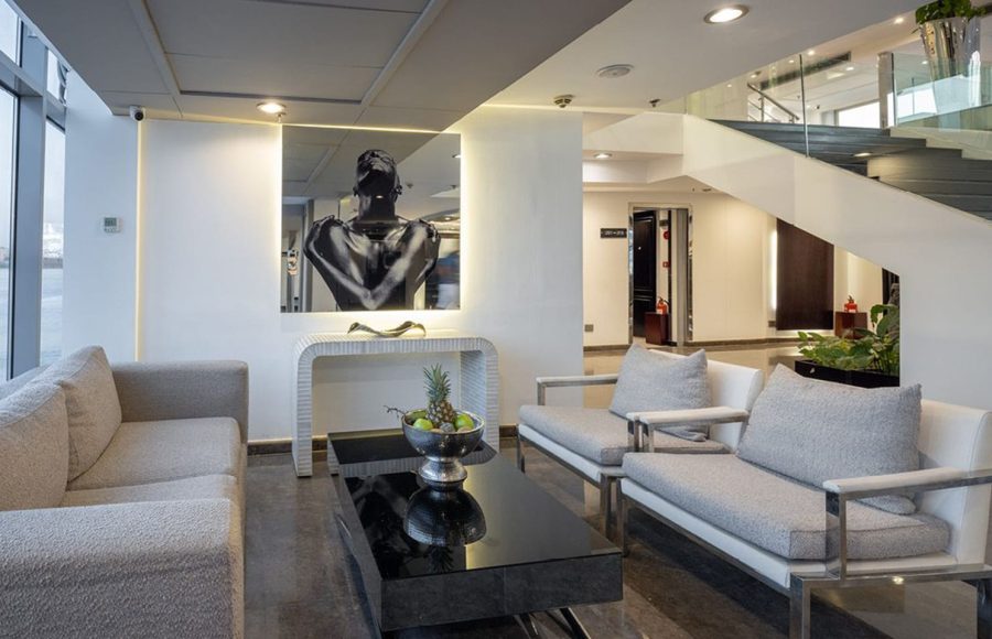 Contemporary seating area in the MS Farah lobby with gray sofas, a black coffee table, and a staircase in the background.