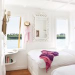 A bright white twin cabin on a Nile boat with two beds, large windows, and an ornate mirror.