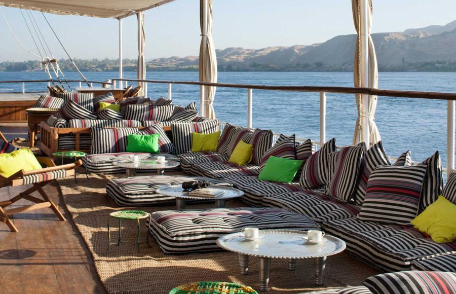 Sundeck of a Dahabiya boat on the Nile with striped cushions and low tables.