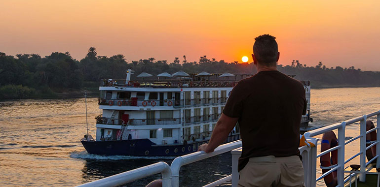 Man leaning over the railing at sunset in the Nile river