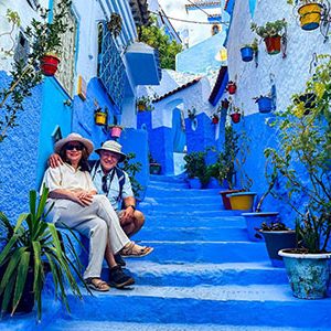 Mature couple posing on stairway in Chefchaouen Morocco during their 18 day Egypt Morocco Chefchaouen Fez Marrakech tour
