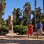 Couple standing next to a statue of Ramses II in Memphis during a wonderful Memphis day trip from Cairo