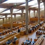 The ultra-modern, spacious main reading area of the Alexandria Library, featuring towering angled columns and tiered rows of desks.