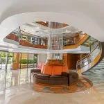 Indoor cruise ship salon with plush seating, central wooden bar, and red accents.