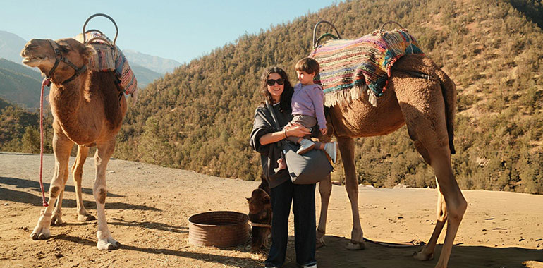 Mother holding child near camel in Atlas Mountains