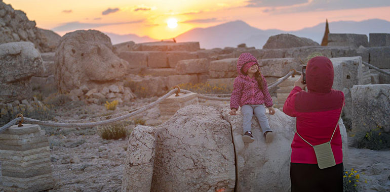 Mother photographing daughter in ancient ruins at mount nemrut Adiyaman