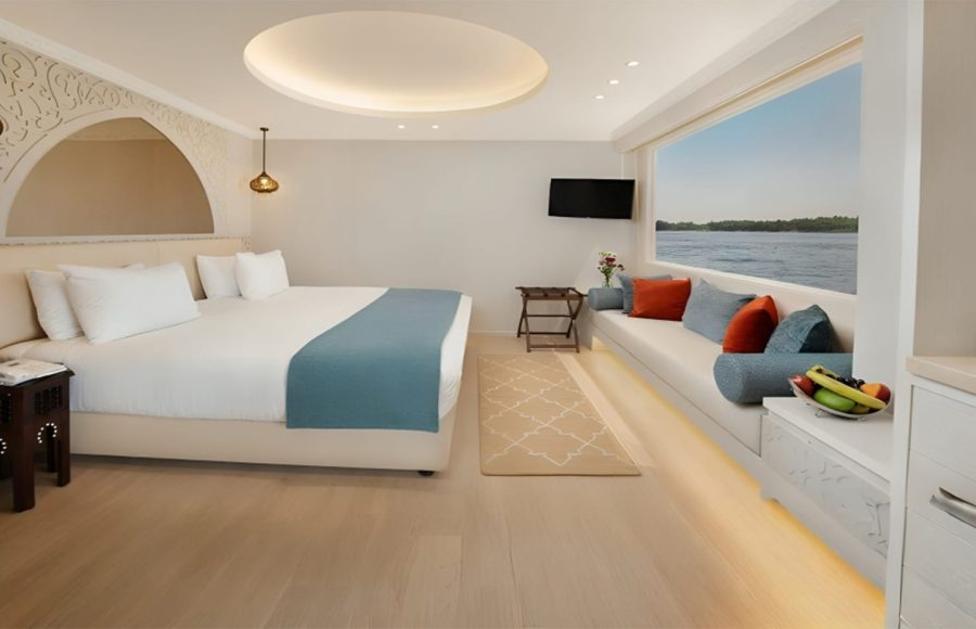 Nile cruise suite with a king bed and large window overlooking the water