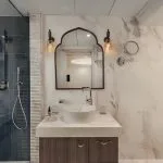 Luxury cruise bathroom with marble walls and blue tiled shower.