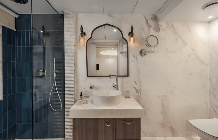 Luxury cruise bathroom with marble walls and blue tiled shower.