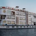 Short Alternative Text: Exterior of the white H.S. Nebu Nile Cruise ship sailing on the river.