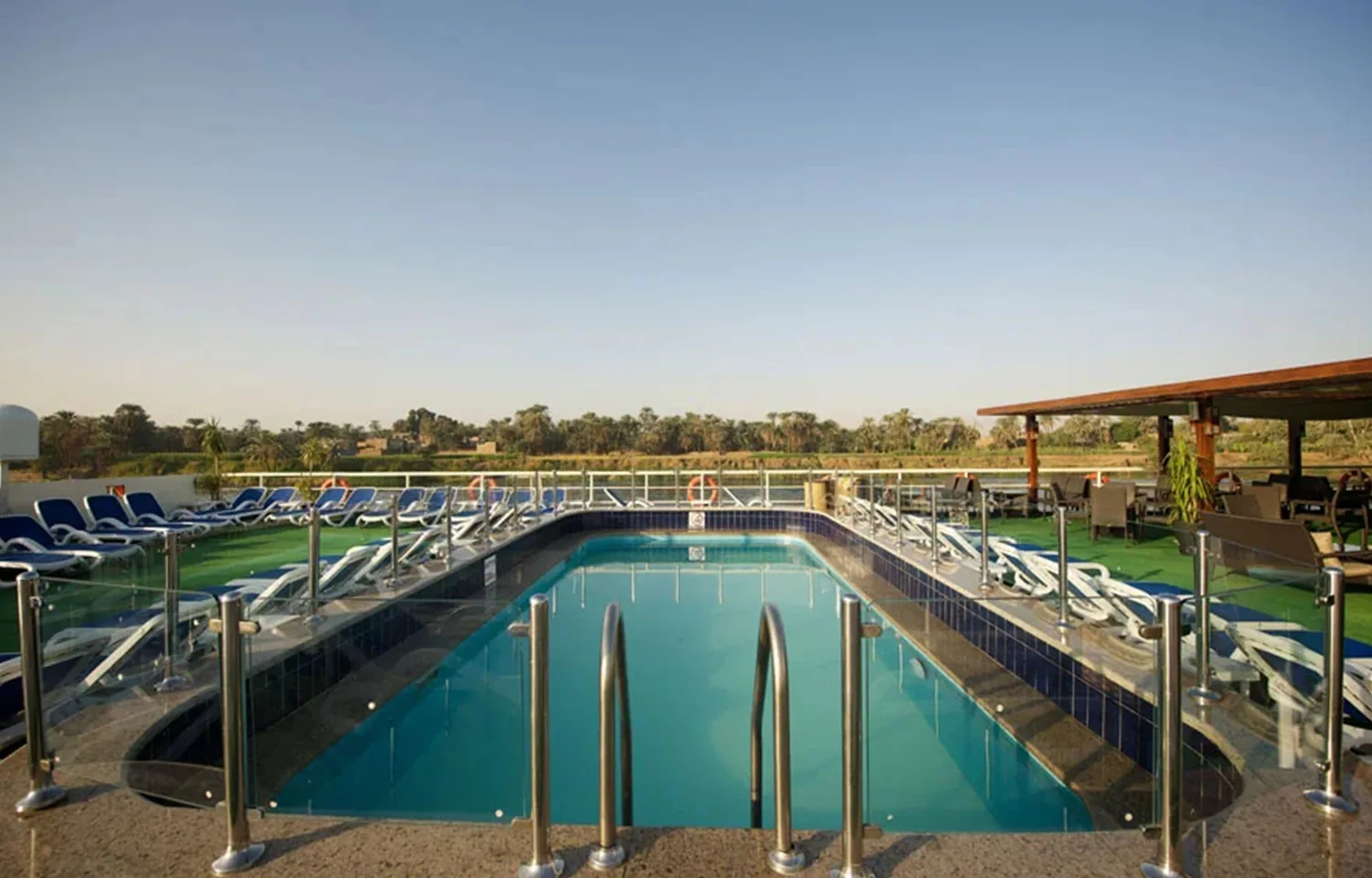 Sun deck with a rectangular pool overlooking the Nile River on the Commodore Nile Cruise ship.