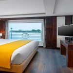 A spacious suite with large windows offering panoramic views of the Nile River, a feature of your luxurious Nile Cruise with Red Sea Stay.