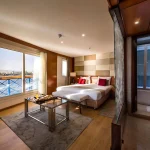 A lavish cruise suite with a large window offering a view of the Nile, perfect for the Lake Nasser and Nile Cruise Itinerary.